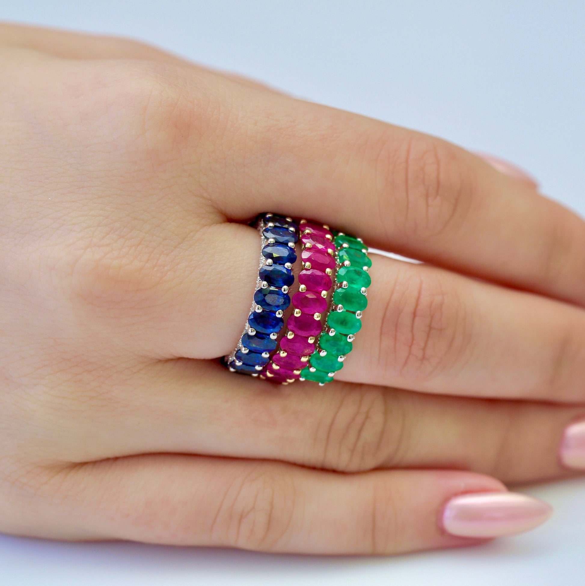 Model wearing Blue, Red and green gemstone rings on middle finger